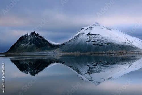 Volcanic mountains in winter with reflection in the water, near Djupivogur, East Island, Island photo