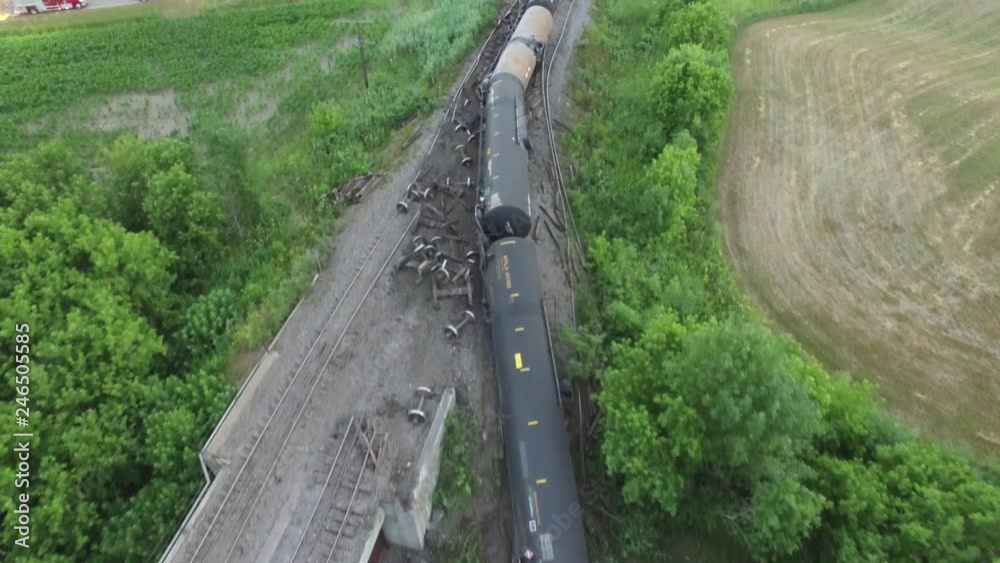 Oil tank cars laying on river embankment after train crash menacing nature
