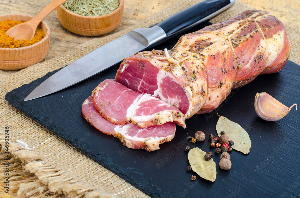 Traditional smoked pork neck with herbs and spices on wooden table