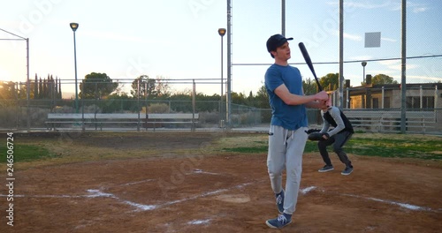 A baseball player swings his bat missing a pitch which causes him to strikeout ending the inning during a park game at sunset.