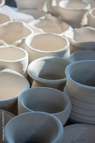 Handicraft production of clay pots. Handmade ceramics before firing. A lot of dishes from clay on the table. Close-up