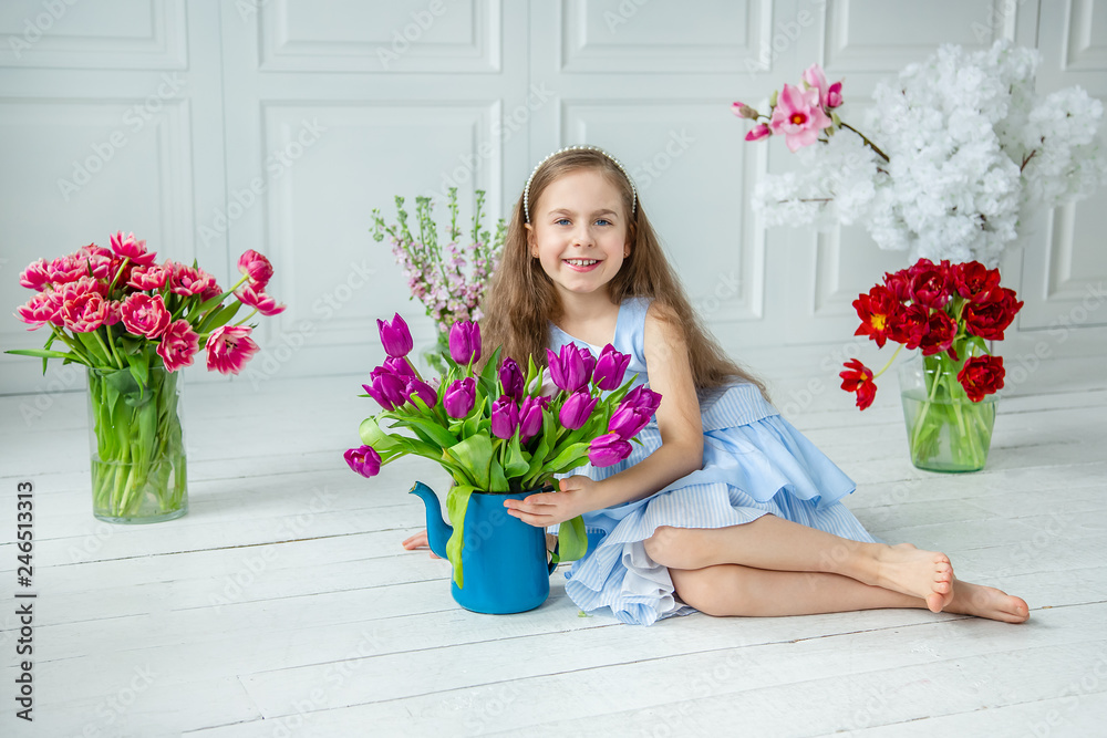 Portrait of a beautiful blue-eyed child, a little girl with a bouquet of tulips in a bright room.