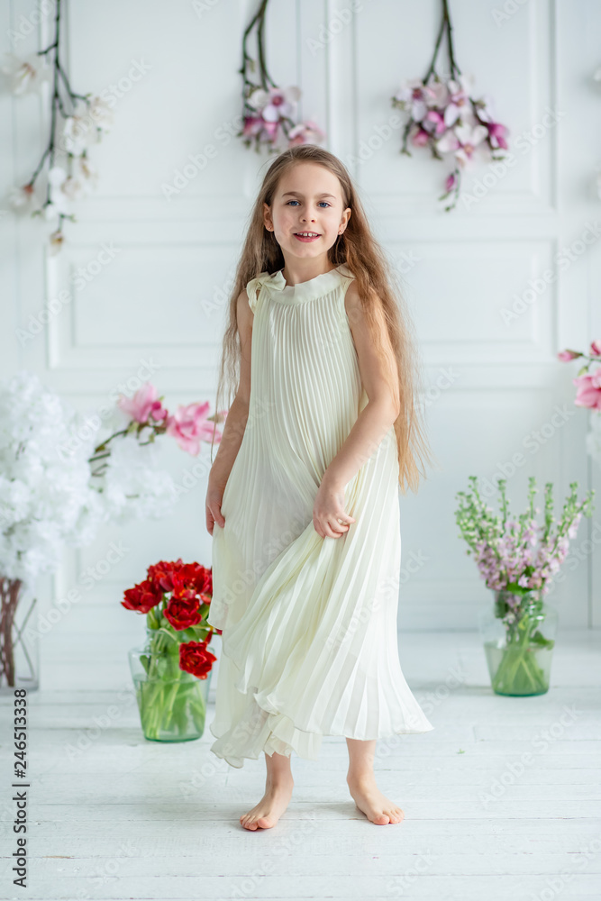 Portrait of a beautiful blue-eyed child, a little girl with a bouquet of tulips in a bright room.