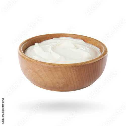 Wooden bowl with delicious sour cream on white background