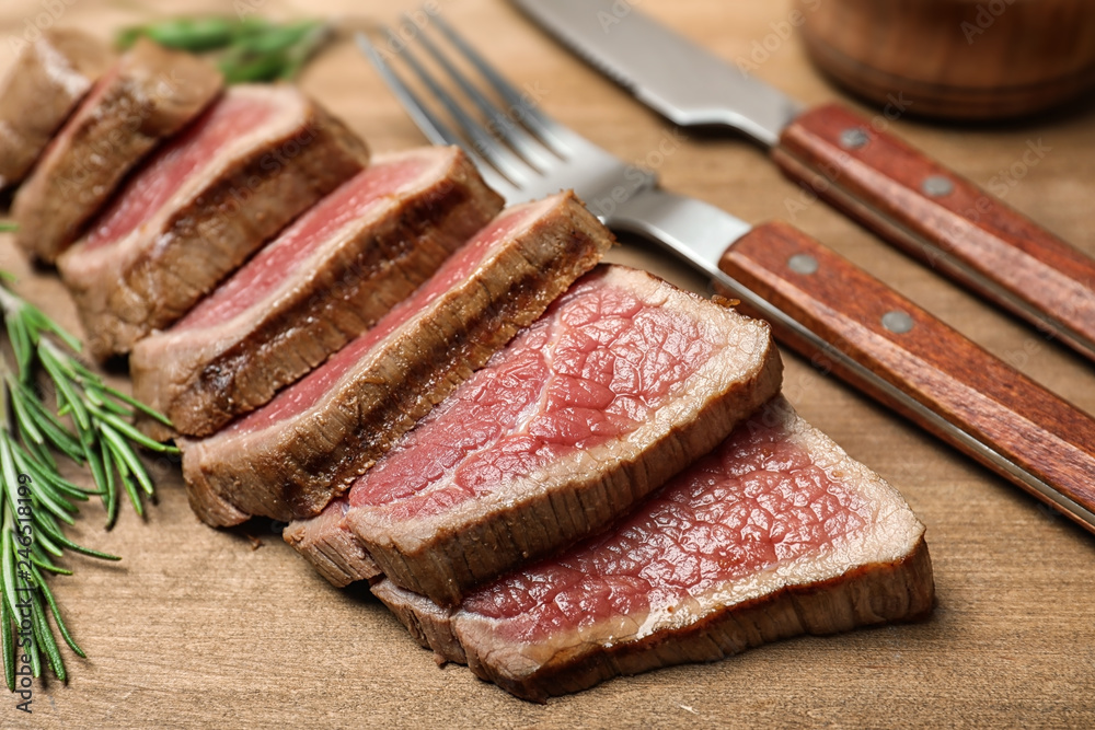 Cut roasted meat with rosemary on wooden background, closeup Cut roasted meat with rosemary on wooden background, closeup