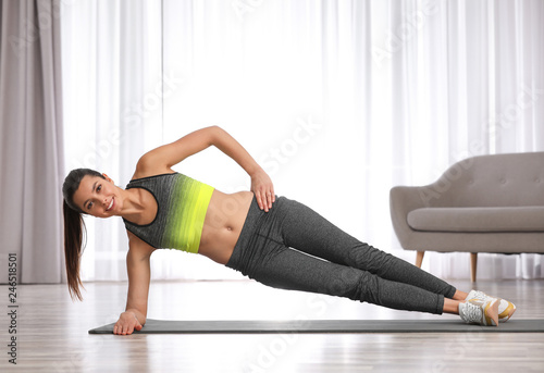 Young woman in fitness clothes doing exercise at home. Space for text