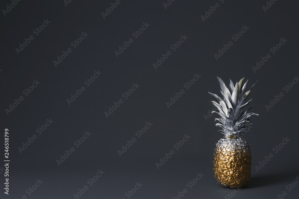 Pineapple painted with silver and gold on dark background. Space for text