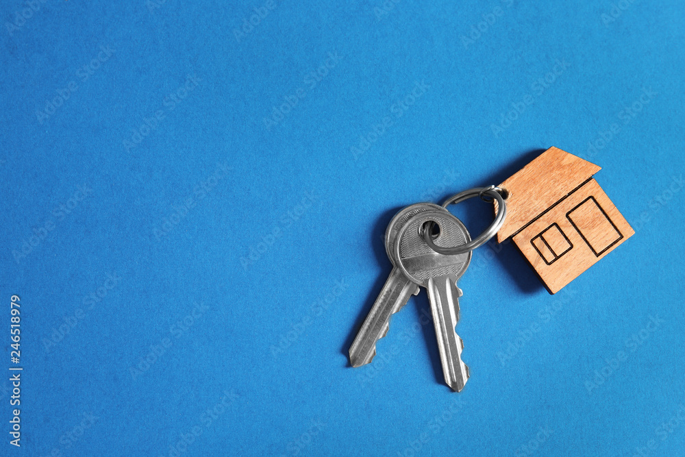 Fototapeta premium House keys with trinket on color background, top view. Space for text