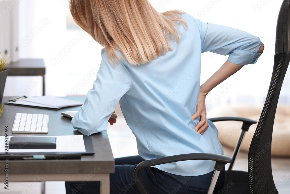 Young woman suffering from back pain in office - obrazy, fototapety, plakaty 