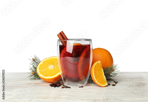 Glass of mulled wine with fir branch, cinnamon and orange on table against white background