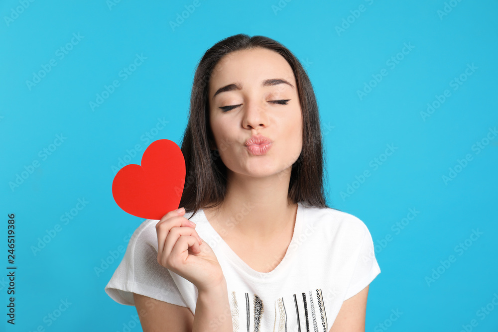 Portrait of beautiful young woman with paper heart on color background Portrait of beautiful young woman with paper heart on color background