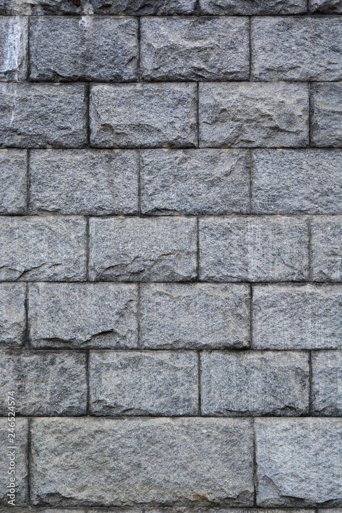 Wall of large granite rough gray stone blocks. Background. Texture. Vertical frame Wall of large granite rough gray stone blocks. Background. Texture. Vertical frame