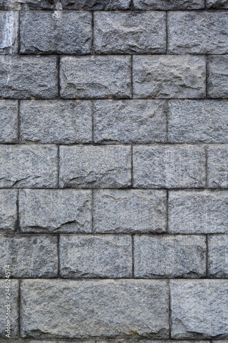 Wall of large granite rough gray stone blocks. Background. Texture. Vertical frame