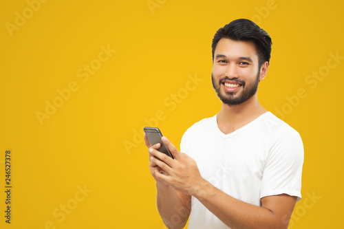 Asian business man handsome man with a mustache, smiling and laughing and using smart phone on yellow background © tuiphotoengineer