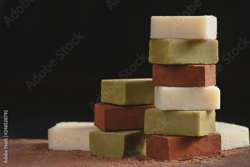 Assortment of soft chocolates on a black background with copy space. Milk and matcha Japanese gourmet chocolate close-up