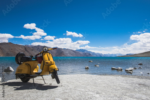 Yellow motocycle in front of clear natural water of lake Pangong in Ladakh, India