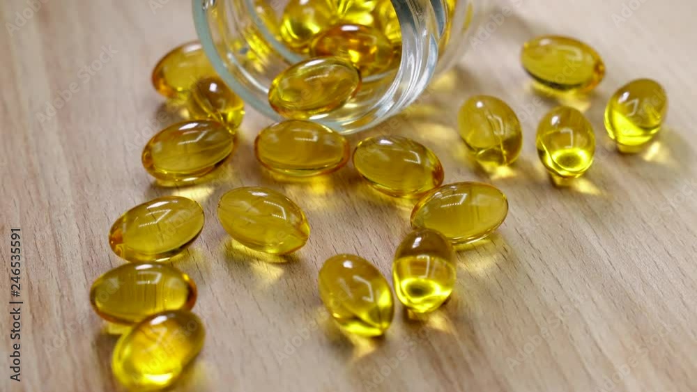Yellow medicine capsules near glass bottle on a wooden table. 4K Yellow medicine capsules near glass bottle on a wooden table. 4K