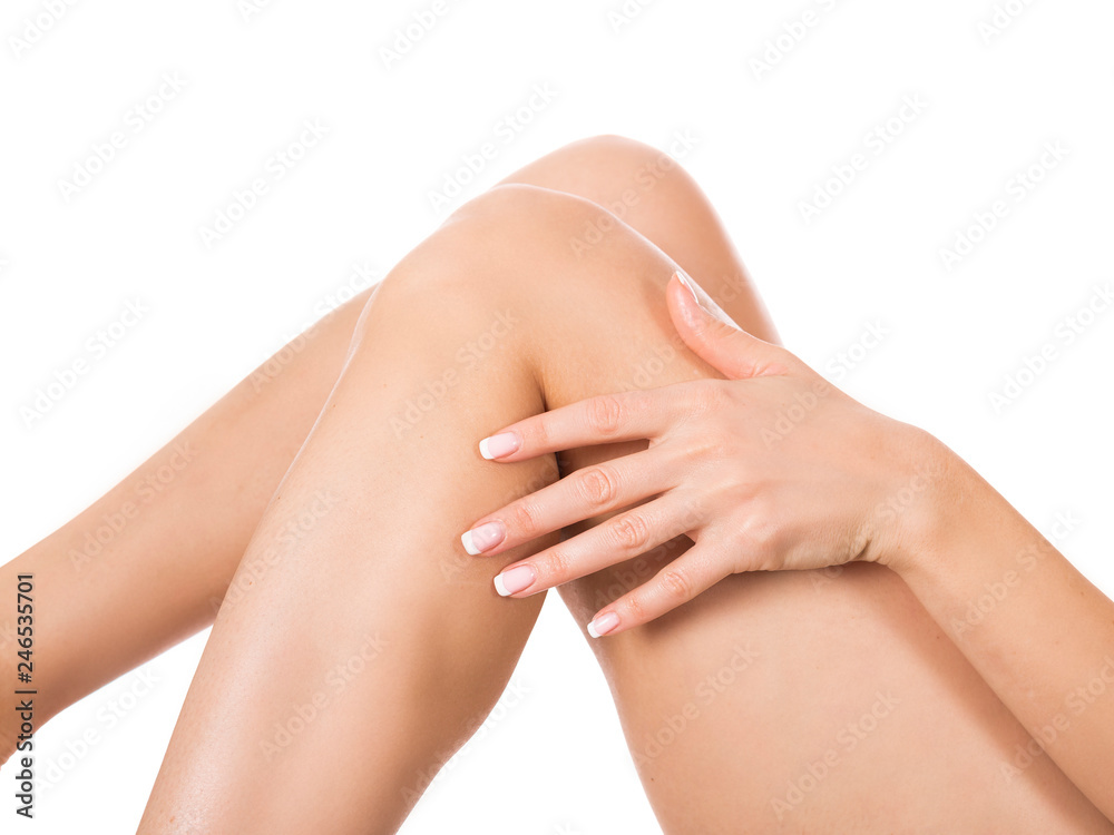 Fototapeta premium Applying moisturizer cream. Care for female legs isolated on white background. Skin care and health concept.