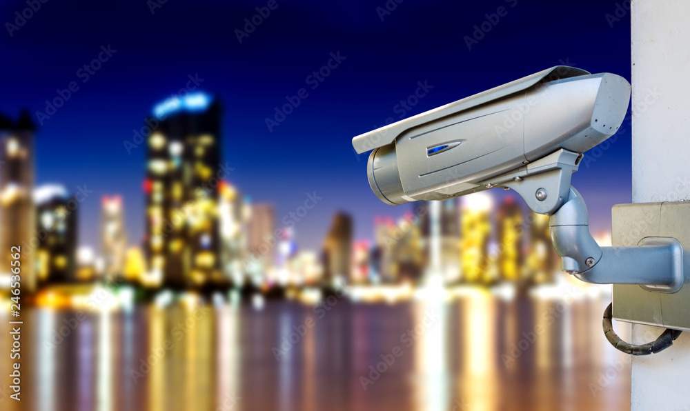 Modern CCTV camera surveillance and monitoring event on blurred night capital city background.