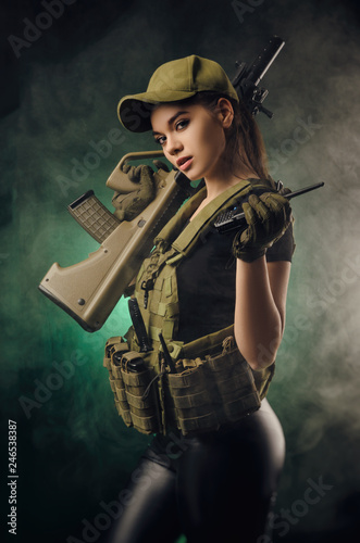 the girl in military special clothes posing with a gun in his hands on a dark ba Fototapet