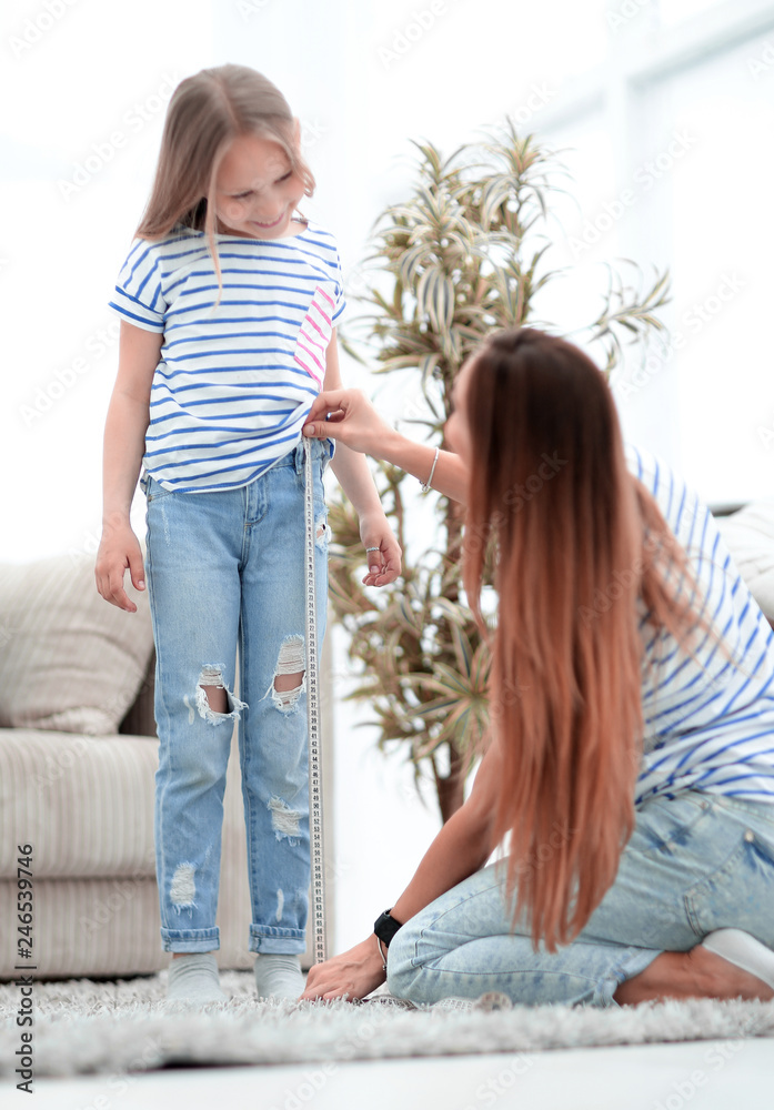 mom checks the length of her daughter's jeans