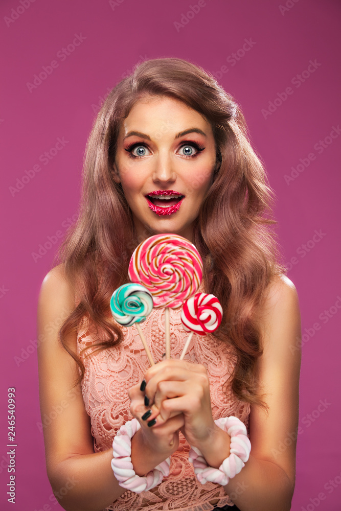 Beautiful pink lips with a sweet candy lollypop. Close up portret of young woman with candy in mouth.
