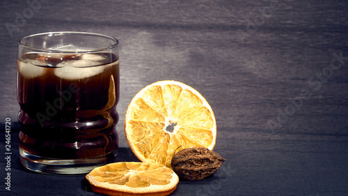 Drink with ice in a stanie on a dark background and oranges. photo