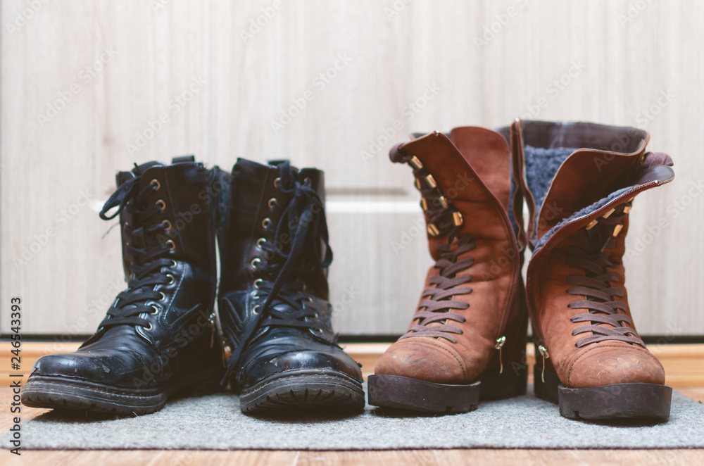 Female suede brown shoes and worn out male black leather boots on the floor in a hallway. Female suede brown shoes and worn out male black leather boots on the floor in a hallway.
