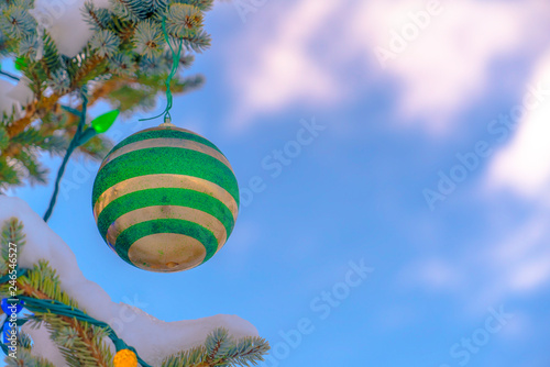 Christmas ball on a tree with lights against sky