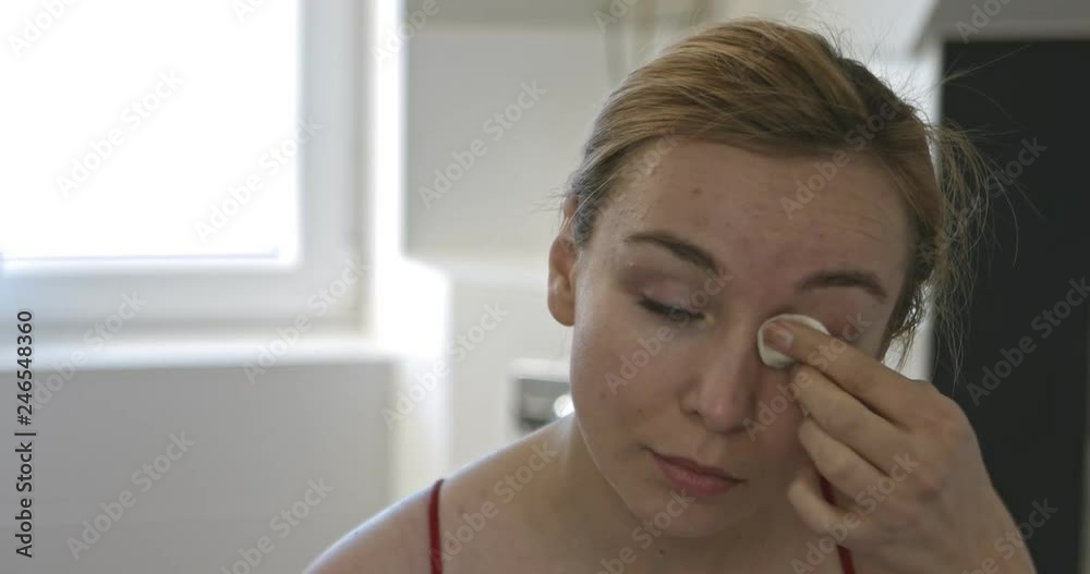 Woman wiping her eyes with cotton pad Woman wiping her eyes with cotton pad