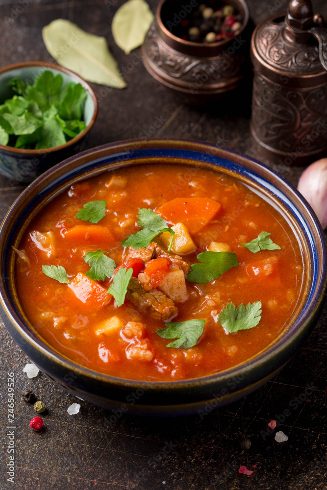 Thick tomato soup with meat, cereals and vegetables. Traditional Oriental cuisine, spicy stew with beef or lamb, rice and spices. Food on dark background Thick tomato soup with meat, cereals and vegetables. Traditional Oriental cuisine, spicy stew with beef or lamb, rice and spices. Food on dark background