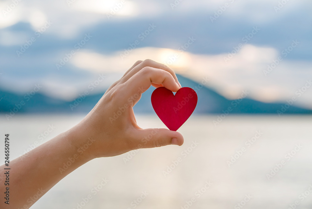 Fototapeta premium Girl holding a symbol of love over the sea 