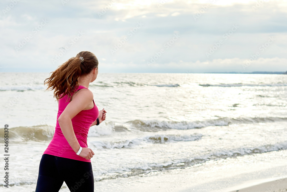 Young fitness woman runner running at seaside, copy space. Girl working out on beach at summer morning, back view. Healthy lifestyle concept Young fitness woman runner running at seaside, copy space. Girl working out on beach at summer morning, back view. Healthy lifestyle concept
