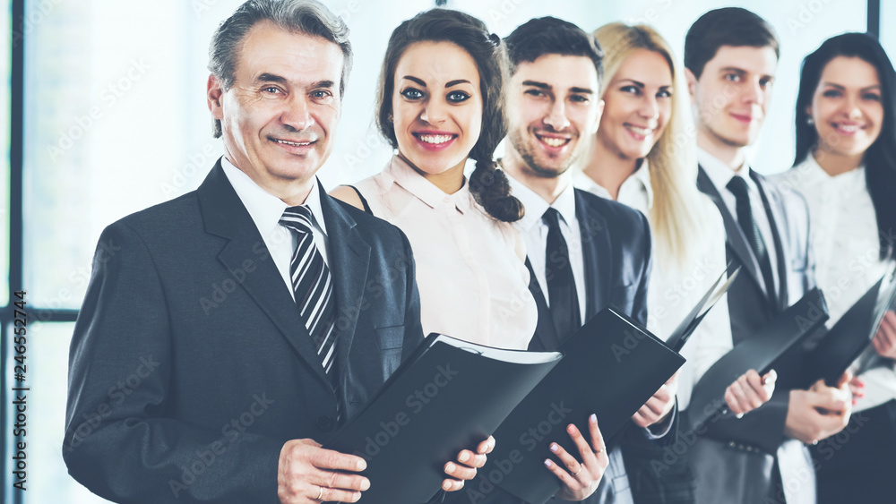 A group of businessmen standing one after another with folders in their hands A group of businessmen standing one after another with folders in their hands