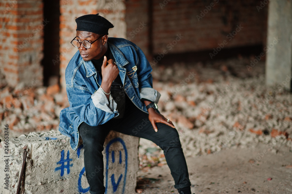 African american man in jeans jacket, beret and eyeglasses at abandoned brick factory. African american man in jeans jacket, beret and eyeglasses at abandoned brick factory.