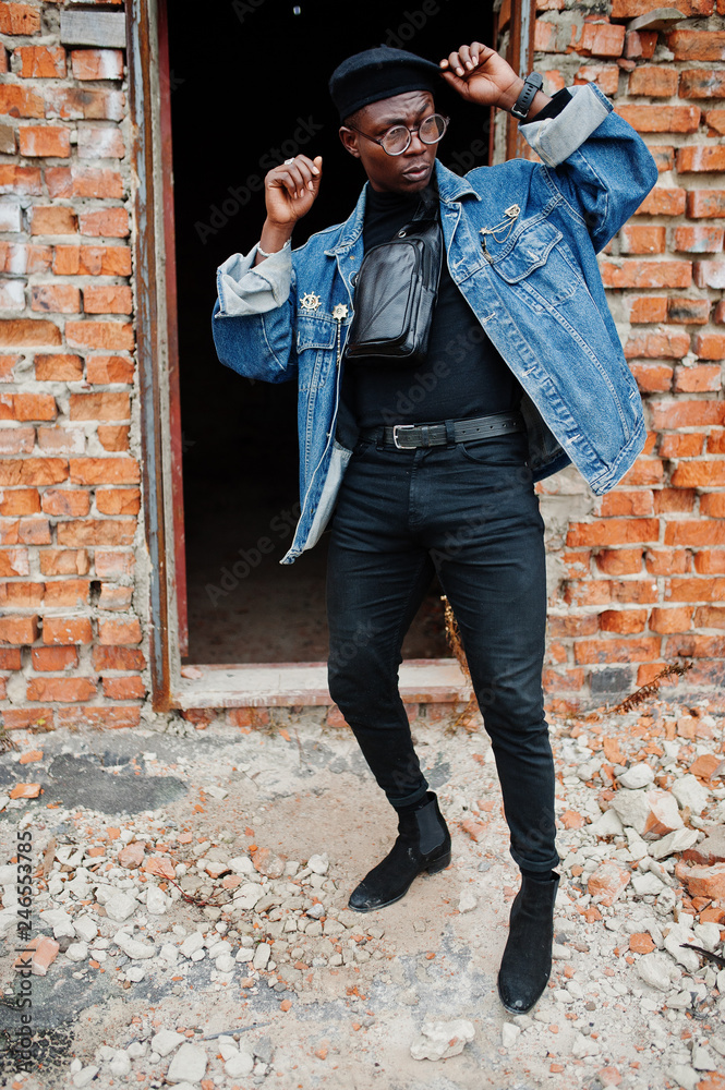 African american man in jeans jacket, beret and eyeglasses against brick  wall at abandoned roof. Photos | Adobe Stock