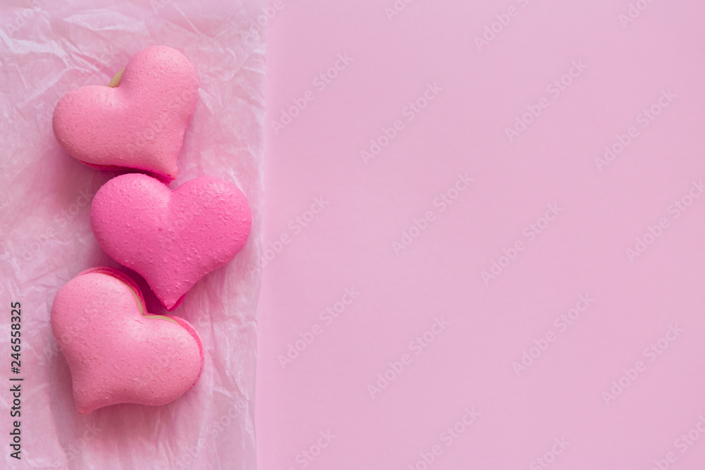 heart-shaped macaroons on pink background.Macaroons Heart.Valentine's Day.Pink gift tied with rosy ribbon and macaron macaroon cookie on pink heart background top view. Valentines Day, 8 March, Womens