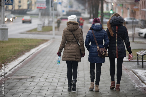 Three young ladies walk in the city of Minsk, rear view