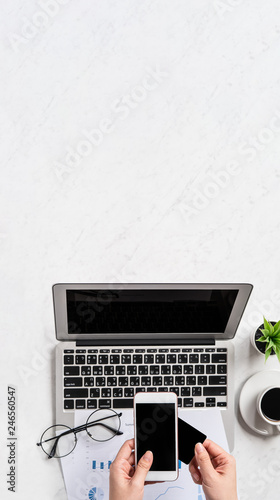 A woman is doing a online payment or shopping, mock up credit card and mobile phone on office desk isolated on beautiful fashion marble background, topview, flatlay, copyspace.