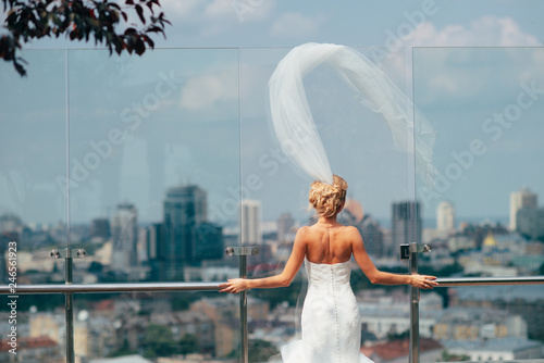 Bride in the morning in a white dress standing on the balcony overlookin the city photo