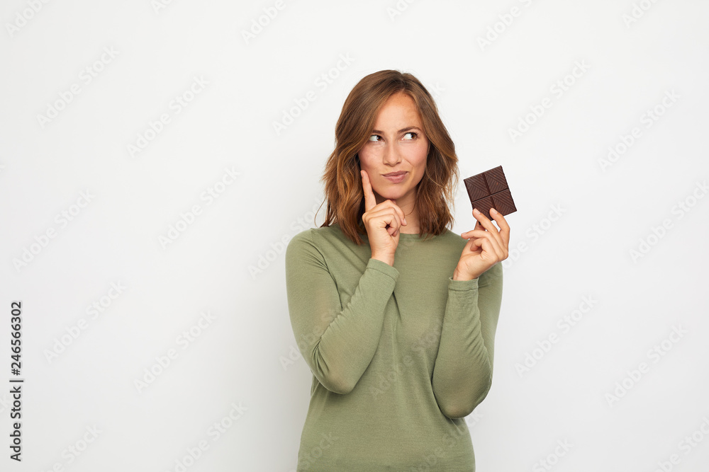 Naklejka premium portrait of young woman with chocolate thinking