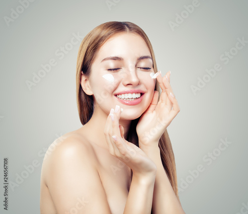 Beautiful woman applying cream on her clean healthy skin. Female face. Facial treatment and skin care concept