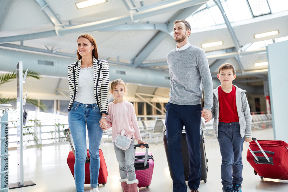 Familie mit Kindern und Koffern im Flughafen