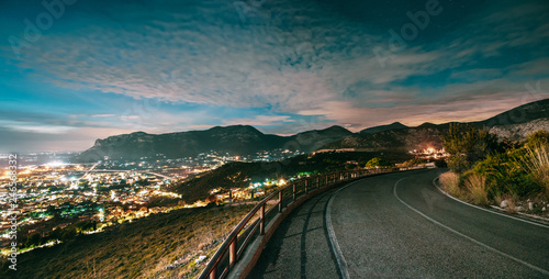 Terracina, Italy. Top View Skyline Cityscape City In Evening Night Illuminations. Night Open Road And Beautiful Cityscape. Panorama, Panoramic View
