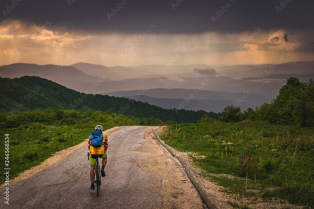 Man cycling in mountain on a rainy day. Stunning view on mountain range from Stara Planina mountain in Serbia. 