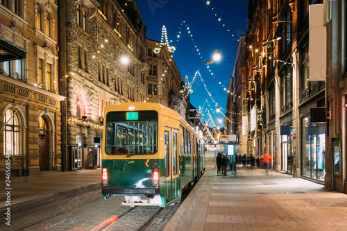 Helsinki, Finland. Tram Departs From Stop On Aleksanterinkatu Street. Night Evening Christmas Xmas New Year Festive Illumination On Street. Beautiful Street Decorations During Winter Holidays photo