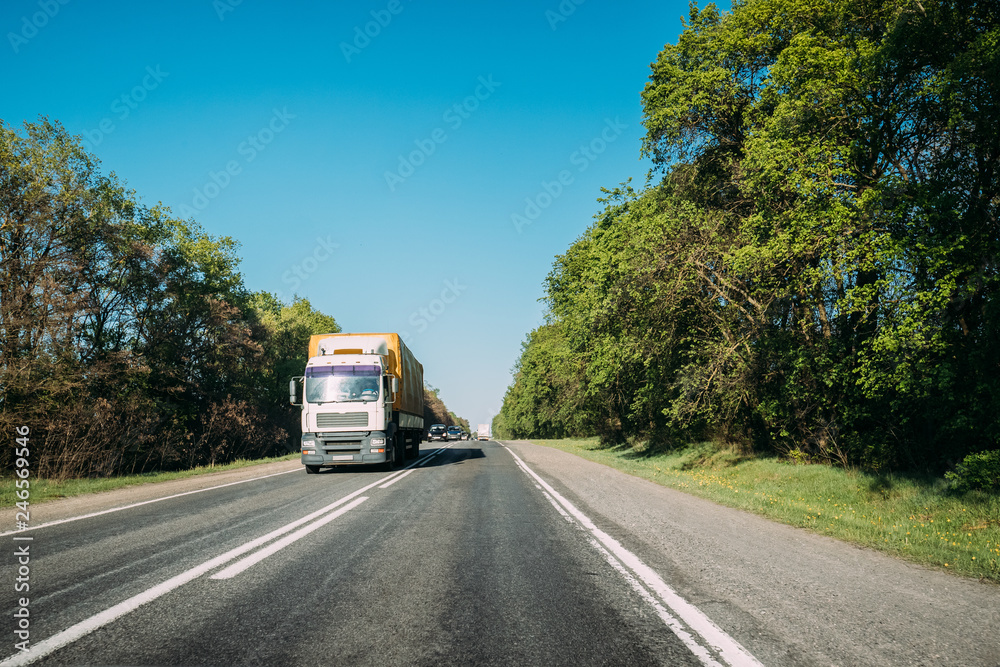 Truck On Country Road. Tractor Unit, Prime Mover, Traction Unit In Motion On Countryside Road In Europe. Business Transportation And Trucking Industry Concept Truck On Country Road. Tractor Unit, Prime Mover, Traction Unit In Motion On Countryside Road In Europe. Business Transportation And Trucking Industry Concept