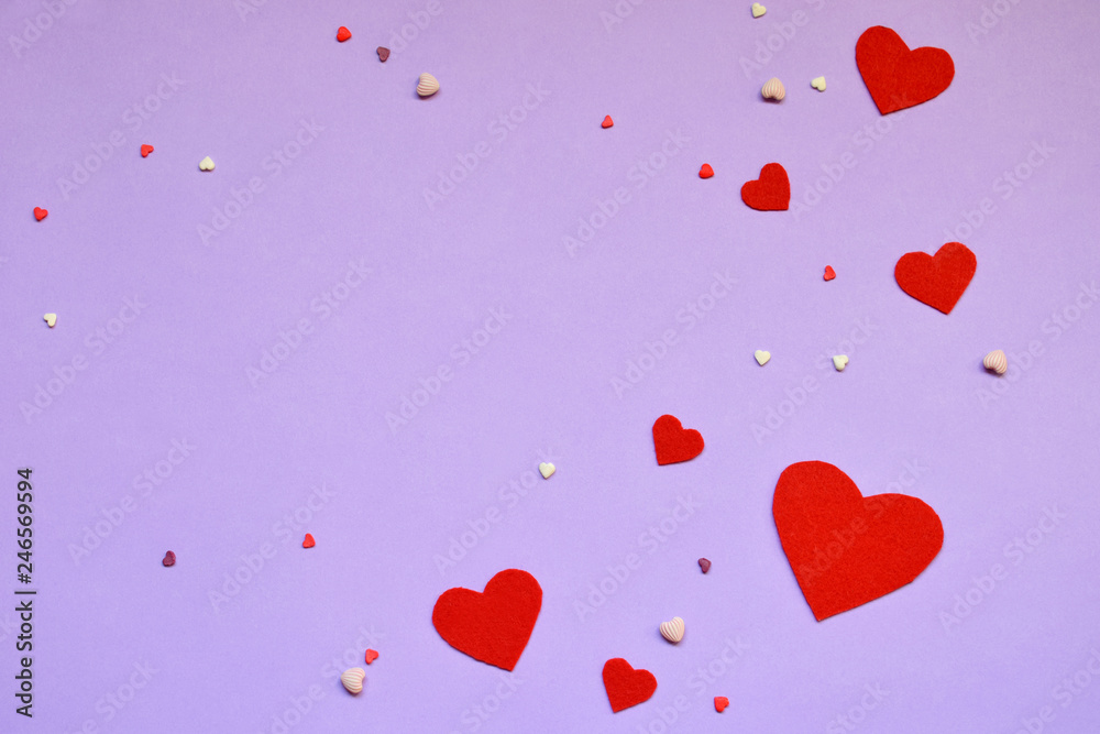 Red felt hearts on pink paper. Valentine's Day background or greeting card concept.