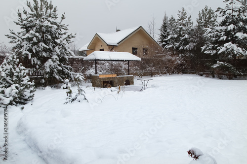 Backyard Patio.Landscape  with barbeque area, snowbanks of white snow, pine trees in country garden. Country life concept.