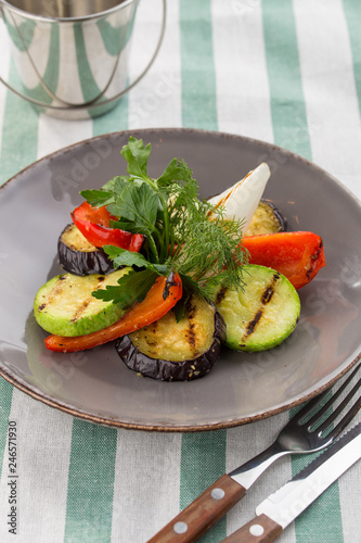 Grilled vegetables zucchini, bell pepper and fresh dill and parsley on the plate on textile background